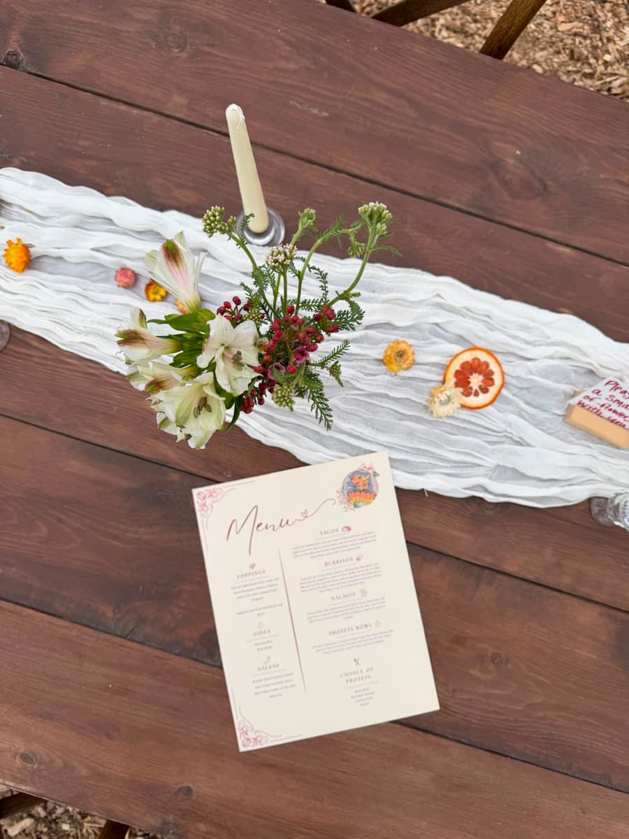 Rustic wedding dining table with runner, candle, floral centerpiece and menu card